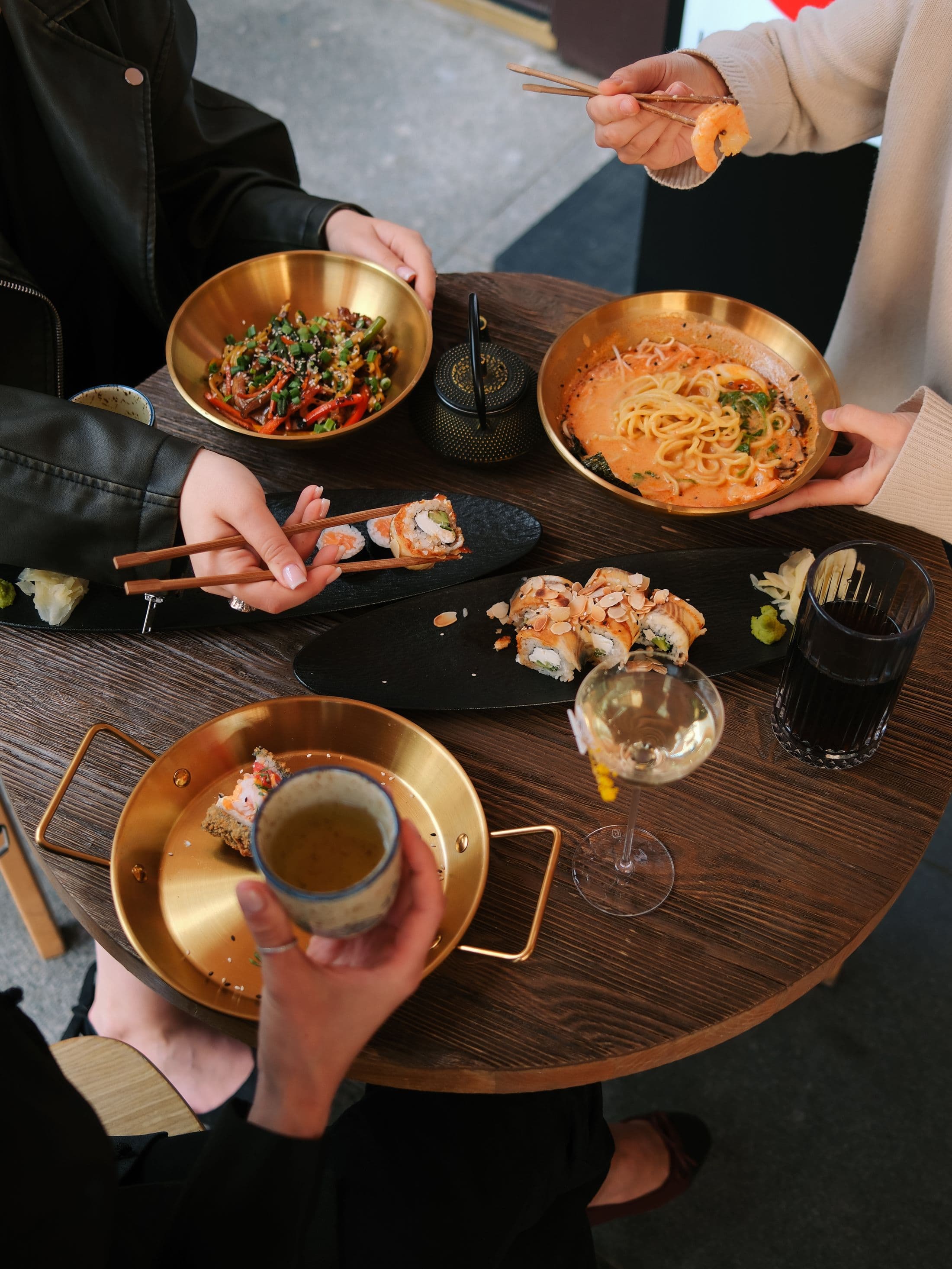 Friends sharing ramen and sushi around a restaurant table